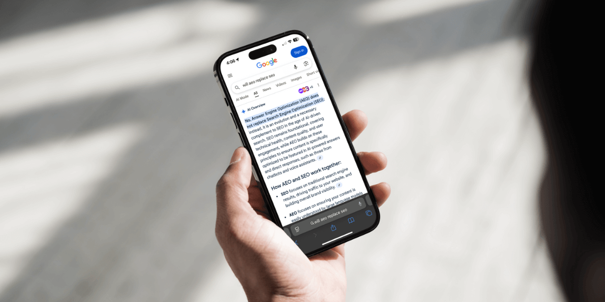 A person holding an Iphone, using the search engine to google the question, Will AEO replace SEO 