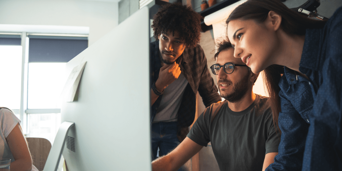 A team of three marketers reviewing HubSpot's AI tools on a large silver desktop.