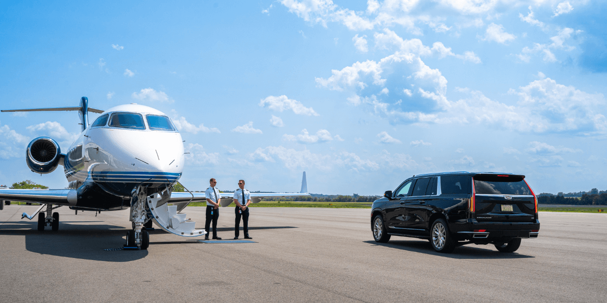 Chantilly Air airplane on the tarmac with 2 employees standing outside of the plane to great clients coming out of a SUV.