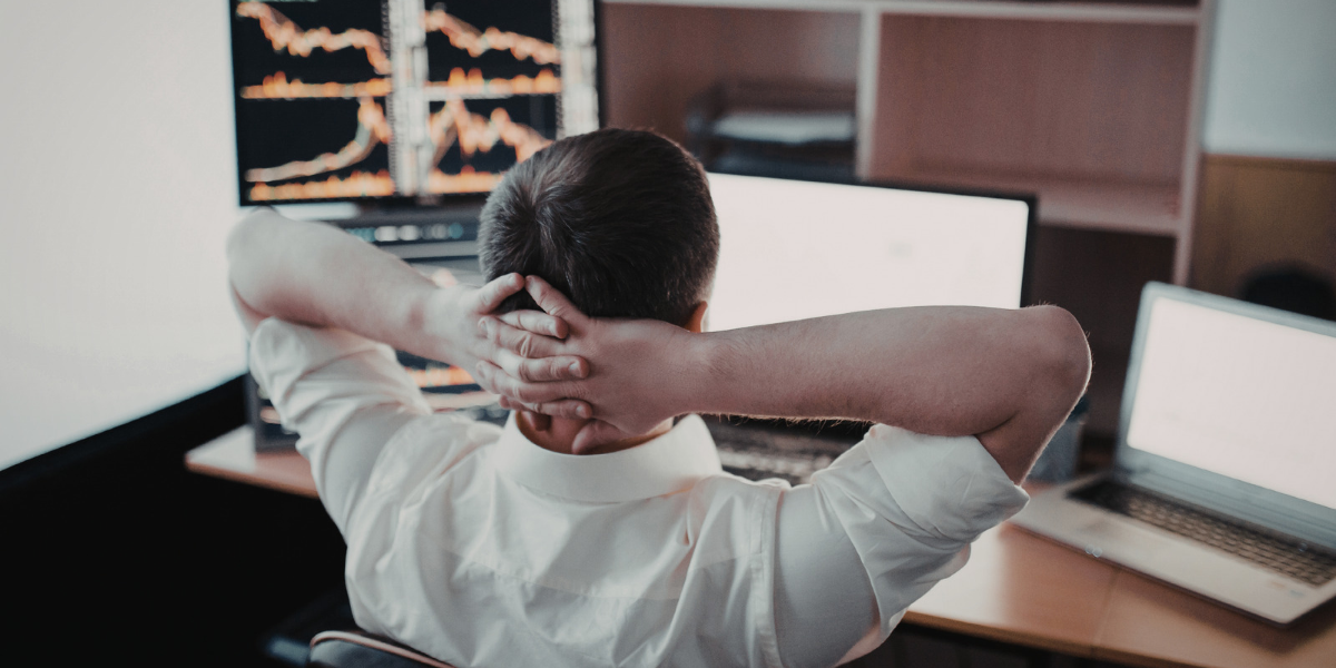 Marketer leaning back with hands behind his head, reviewing CRM performance charts on multiple monitors