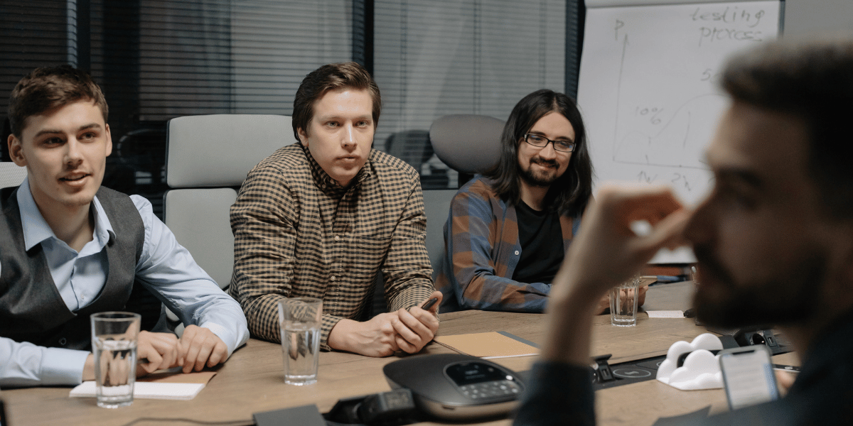 Several male team members sitting at conference desk discussing CRM customization in HubSpot for marketing and sales