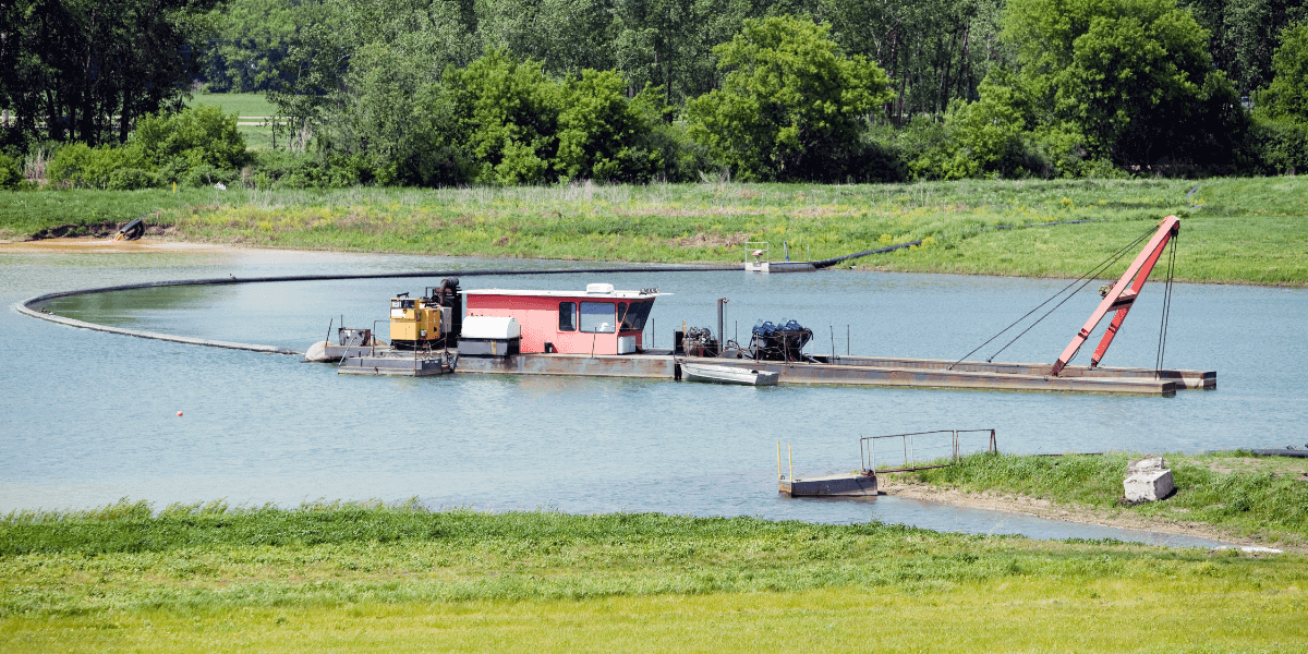 A dredging vehicle in the middle of a small pond