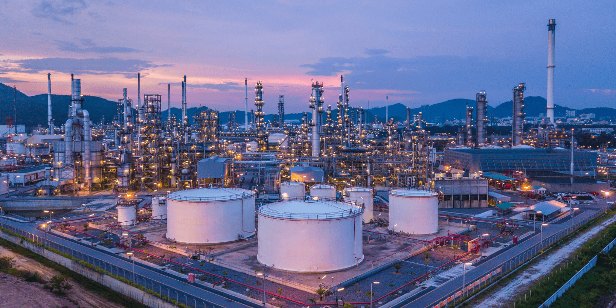 Aerial view of an oil and gas chemical tank with oil refinery plant in the background at twilight.