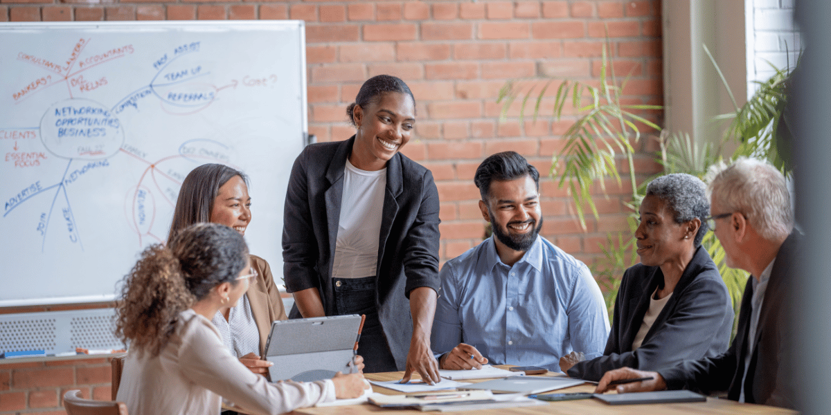 Marketing professionals gathered around a desk with whiteboard in background