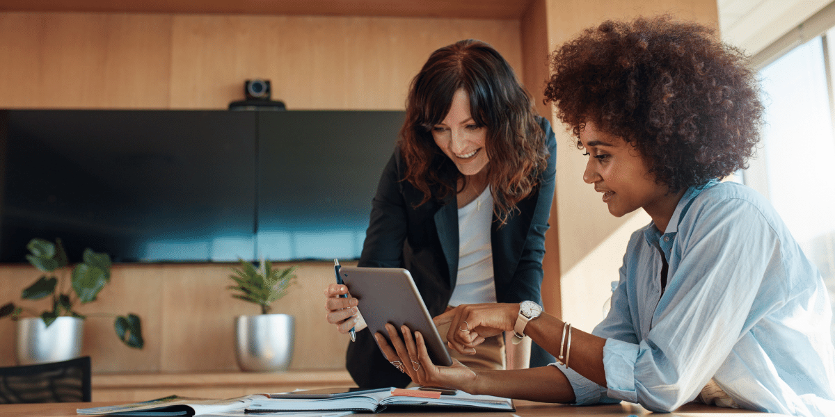 two women looking at a tablet screen at work