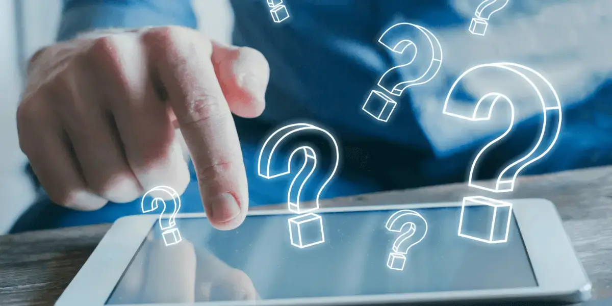 Person pointing at a tablet screen with digital question mark icons floating above, symbolizing curiosity and searching for answers.