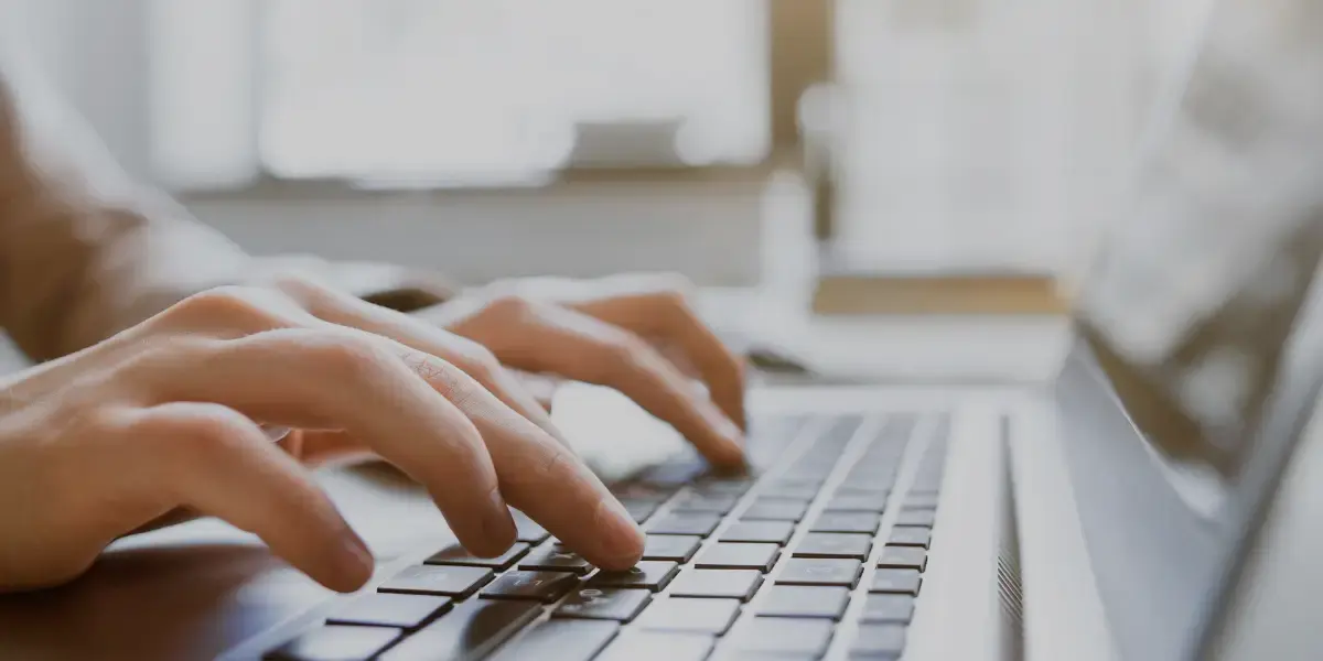 Vesteds New Close-up of hands typing on a laptop keyboard, representing digital work, online research, or content creation.